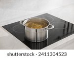 Pot with delicious soup on cooktop in kitchen