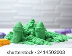 Small photo of Castle figures made of green kinetic sand on white table, closeup