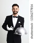 Small photo of Waiter with tray and cloche on light background