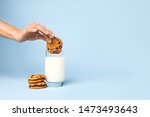 Woman dipping tasty cookie in glass of milk on color background