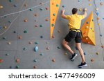Young Man Climbing Wall In Gym