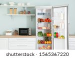 Open big fridge with products in kitchen