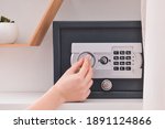 Woman opening modern safe indoors