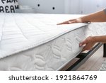 Small photo of Woman putting soft orthopedic mattress on bed