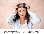 Stressed woman with graying hair on color background