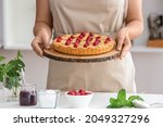 Woman with tasty raspberry pie in kitchen, closeup