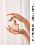 Small photo of Woman with beautiful manicure holding bottle of perfume on light background