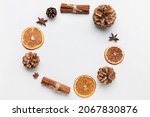 Frame made of pine cones, spices and dried orange slices on white background