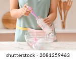 Small photo of Woman cleaning baby bottle at home