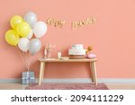 Table with birthday cake and balloons near color wall