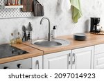 Small photo of Wooden counter with silver sink and utensils near light wall in kitchen