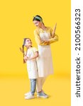 Small photo of Young mother and daughter with kitchen utensils on color background