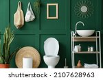 Interior of restroom with toilet bowl, sink and green wall