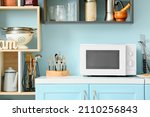White microwave oven on blue counter in stylish kitchen