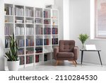 Bookcase with armchair in modern interior of room