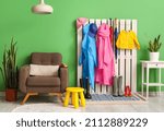 Small photo of Interior of stylish hall with raincoats, gumboots and armchair