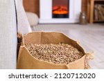 Bag with wood pellets near sofa in living room, closeup