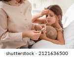 Small photo of Woman measuring temperature of her little girl ill with chickenpox at home