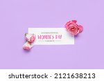 Greeting card for International Women's Day and flowers on lilac background