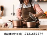 Woman cooking in copper pot at home