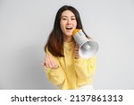 Small photo of Young Asian woman with megaphone inviting viewer on light background