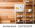 Modern shelving unit with dishware and pegboard near wooden wall in kitchen