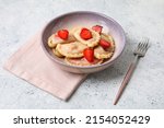 Bowl with tasty strawberry dumplings on light background