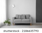 Small photo of Interior of light living room with grey sofa, standard lamp and houseplant