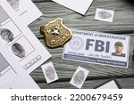 Small photo of Finger prints with document of FBI agent and badge on wooden background