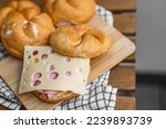 Delicious kaiser rolls with ham and cheese on wooden board