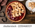 Plate with sweet strawberry pie and heart-shaped plate of cookie hearts for Valentine's day on wooden background