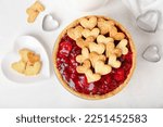 Sweet strawberry pie and heart-shaped plate of cookie hearts for Valentine's day on white background