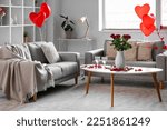 Interior of living room decorated for Valentine's Day with sofas, roses and balloons