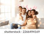 Small photo of Happy interracial family in Easter bunny ears at home
