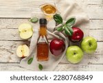 Glass bottle and gravy boat with fresh apple cider vinegar on white wooden background