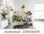 Small photo of Beautiful woman training on treadmill at home