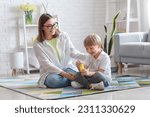 Nanny with little boy blowing soap bubbles at home