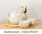 Tea set with wicker mat and flowers  on wooden table