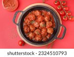 Small photo of Frying pan of tasty meat balls with tomato sauce and dill on red background
