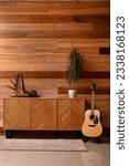 Small photo of Chest of drawers with moose antler, hat, palm tree and guitar in room
