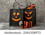 Composition with shopping bags, gift boxes and tasty cookie for Halloween on grunge grey background