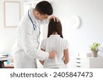 Small photo of Doctor checking posture of little girl in clinic