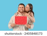 Lovely couple holding greeting card with text I LOVE YOU on blue background. Valentine's Day celebration