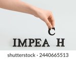 Small photo of Female hand with wooden letters spelling word IMPEACHMENT on white background