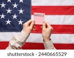 Small photo of Woman holding piece of paper with word IMPEACH against USA flag