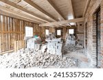 Interior renovation in progress with exposed wooden beams and pile of rubble on the floor in an old house