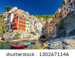 Riomaggiore traditional typical Italian fishing village in National park Cinque Terre with colorful multicolored buildings houses on hill and boats on water, clear blue sky background, Liguria, Italy