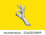 Small photo of The female hand showing the ok gesture isolated on a yellow color background. Trendy abstact 3d collage in magazine urban style. Contemporary art. Modern design. Okay hand sign