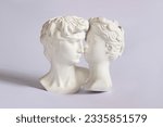 Small photo of Two antique statue's heads isolated on a white background. Relationships of man and woman. Love, romance, kiss, tenderness. Modern design. Contemporary art. David and Aphrodite