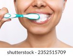 Small photo of Cropped shot of a young smiling woman brushing her teeth with a toothbrush isolated on a white background. Morning and evening routine. Close up. High-quality teeth cleaning with foam formation